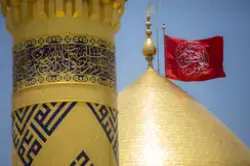 صورة لقبة أبي الفضل العباس يظهر فيها العلم الأحمر مكتوبًا عليه يا قمر بني هاشم في النهار